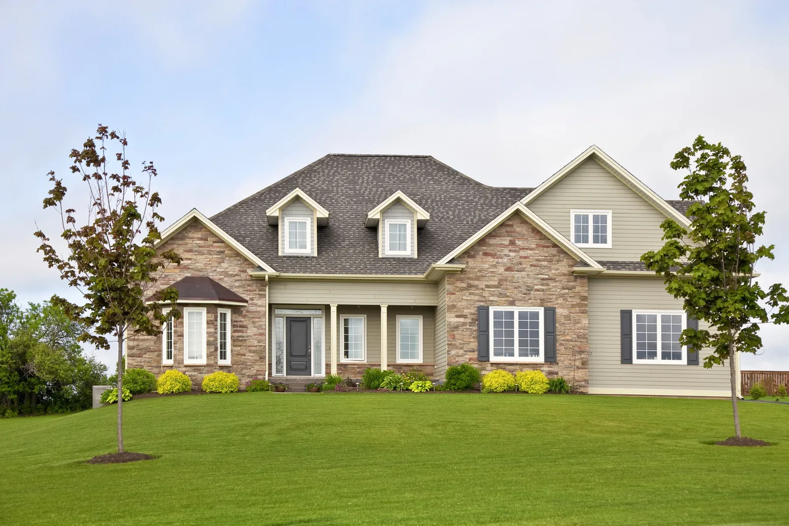 Newly built New England home with landscaped lawn